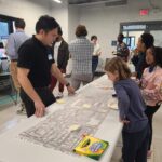 A child looks at a concept for a street while a member of the team explains the project.