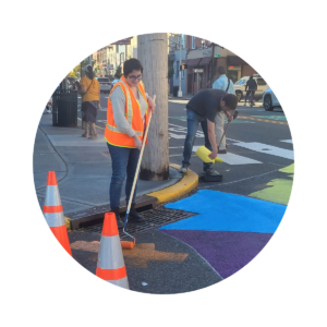 A staff member participates in a traffic calming demonstration using paint on a road.