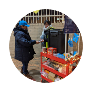 A staff member passes out a survey and hot chocolate to a participant.