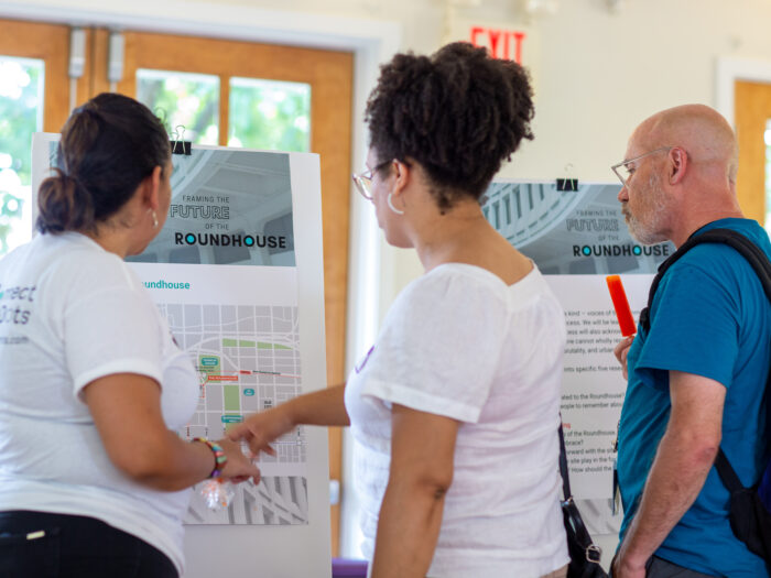 people interact with poster boards during a community engagement event