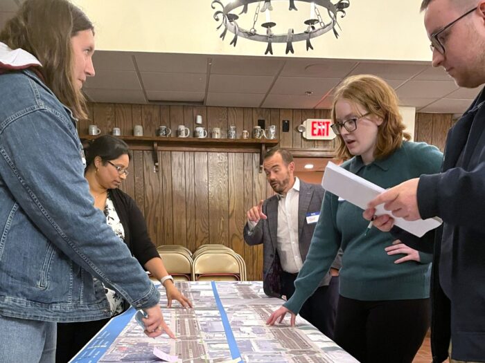 People talking over a roll plot showing Spring Garden Street